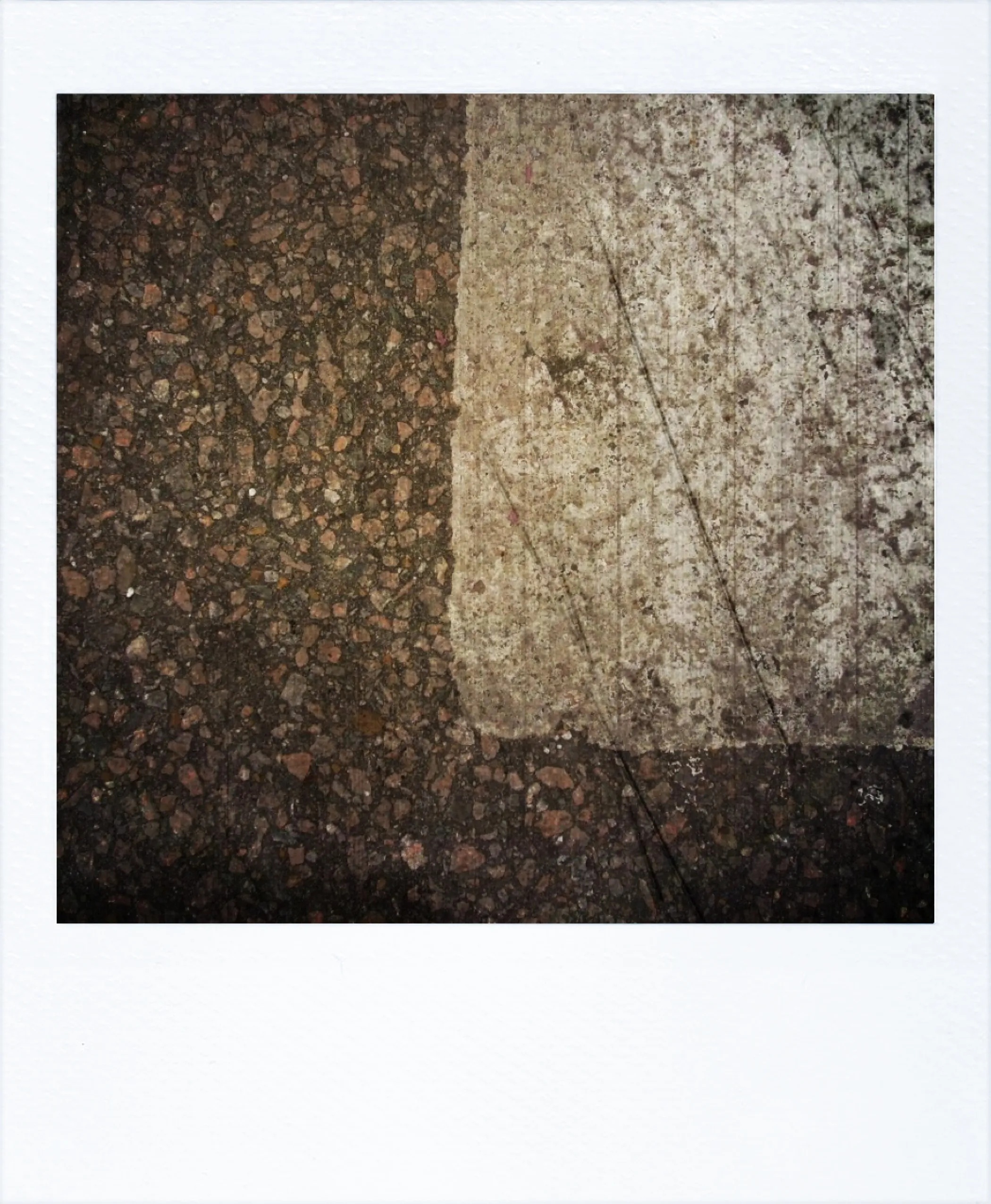 Close-up of a city street where dark asphalt meets a weathered white crosswalk line.