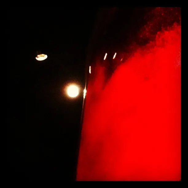 Abstract image showing a glowing red vertical surface or mist on the right, with bright lights against a dark background on the left.