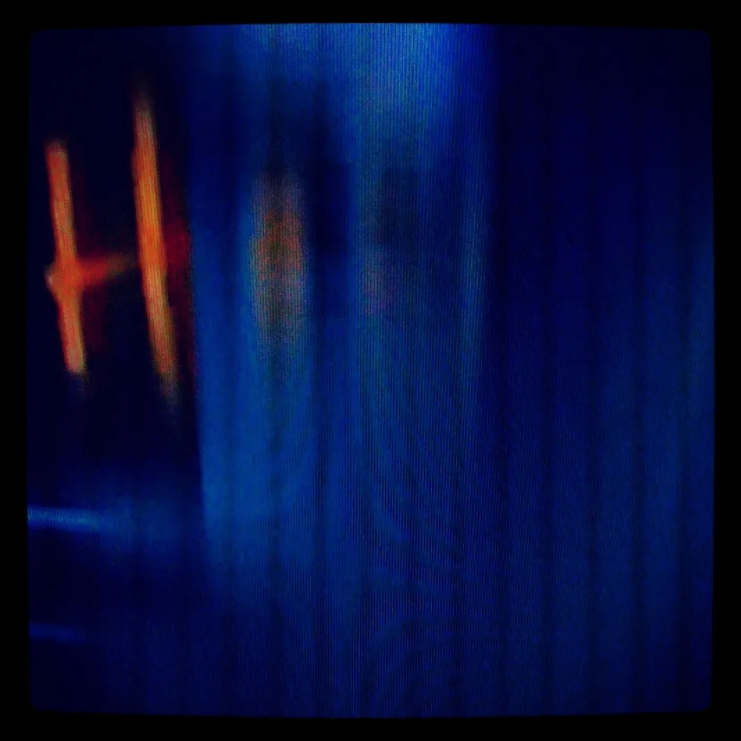 Abstract image of a television screen showing blue vertical scan lines with blurred red and orange shapes on the left side.