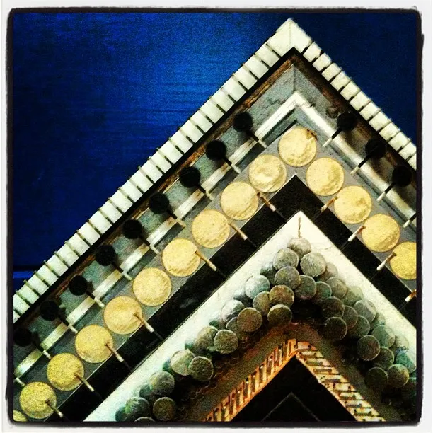A close-up of overlapping picture frame corners, each decorated with round metallic studs, arranged in a triangle pattern.
