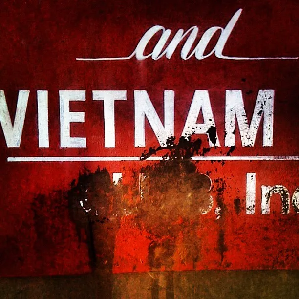 A worn red sign partially reading “and VIETNAM” with black smudges and faded paint obscuring the lower text area.