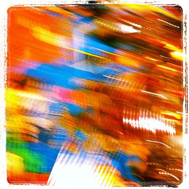 Abstract image with intense motion blur in vibrant hues of red, blue, yellow, and orange, creating a dynamic, swirling pattern.