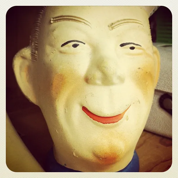 Close-up of a vintage ceramic or plastic mannequin head with painted facial features and a smiling expression.