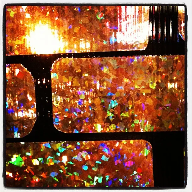 Close-up of iridescent holographic film strips with colorful light reflections in orange, red, and rainbow tones.