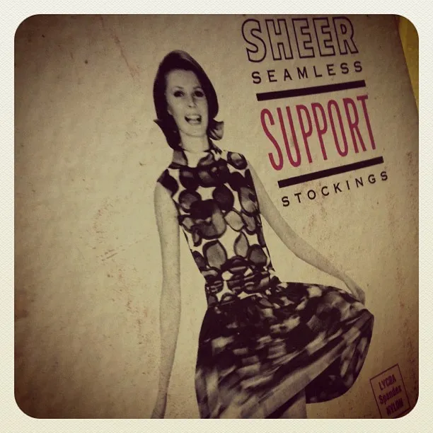Vintage advertisement for “Sheer Seamless Support Stockings” featuring a black-and-white image of a smiling woman in a patterned dress.