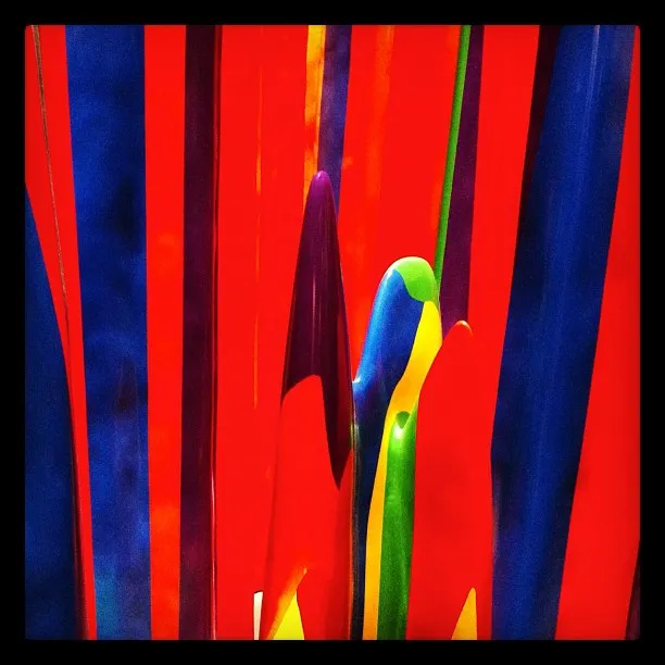 Close-up of colorful vertical glass or plastic rods in red, blue, green, and yellow, creating an abstract pattern.