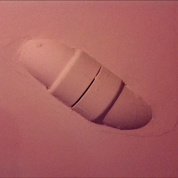 Rounded patch of drywall with three visible seams on a pink-toned wall, suggesting recent repair or construction.
