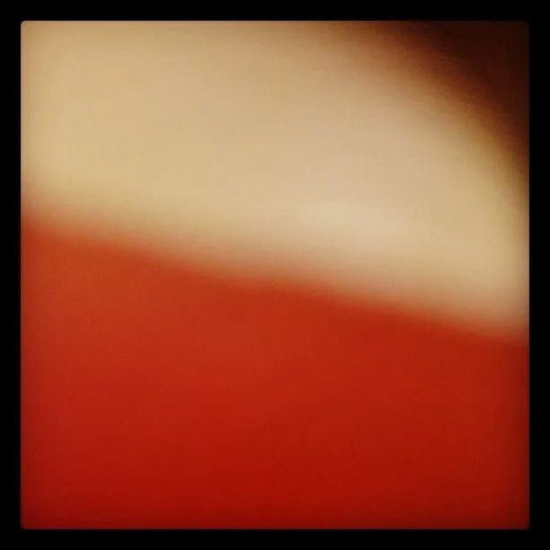 Abstract image with soft gradients of beige and red, separated by a diagonal transition, slightly blurred throughout.