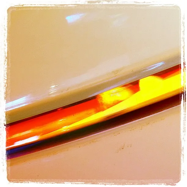 Close-up of a glowing amber side marker light embedded in the smooth, curved surface of a white vehicle.