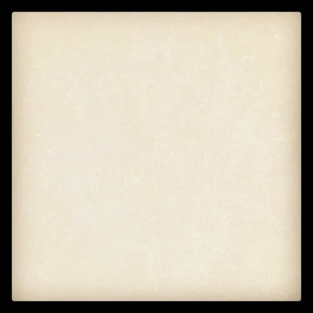 A close-up photograph of a smooth, off-white surface with subtle speckles and a faint vignette effect around the edges.