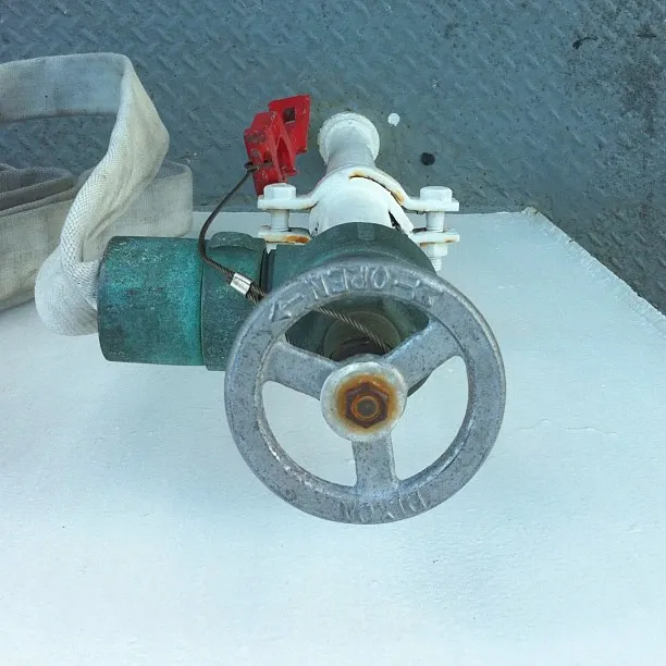 Close-up view of a fire hose valve and wheel assembly mounted on a white platform, with attached hose coiled to the side.