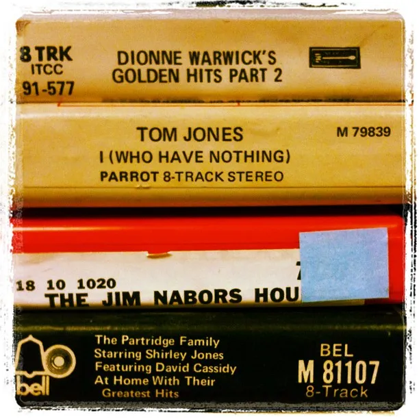 Stack of vintage 8-track tapes featuring artists like Dionne Warwick, Tom Jones, Jim Nabors, and The Partridge Family.