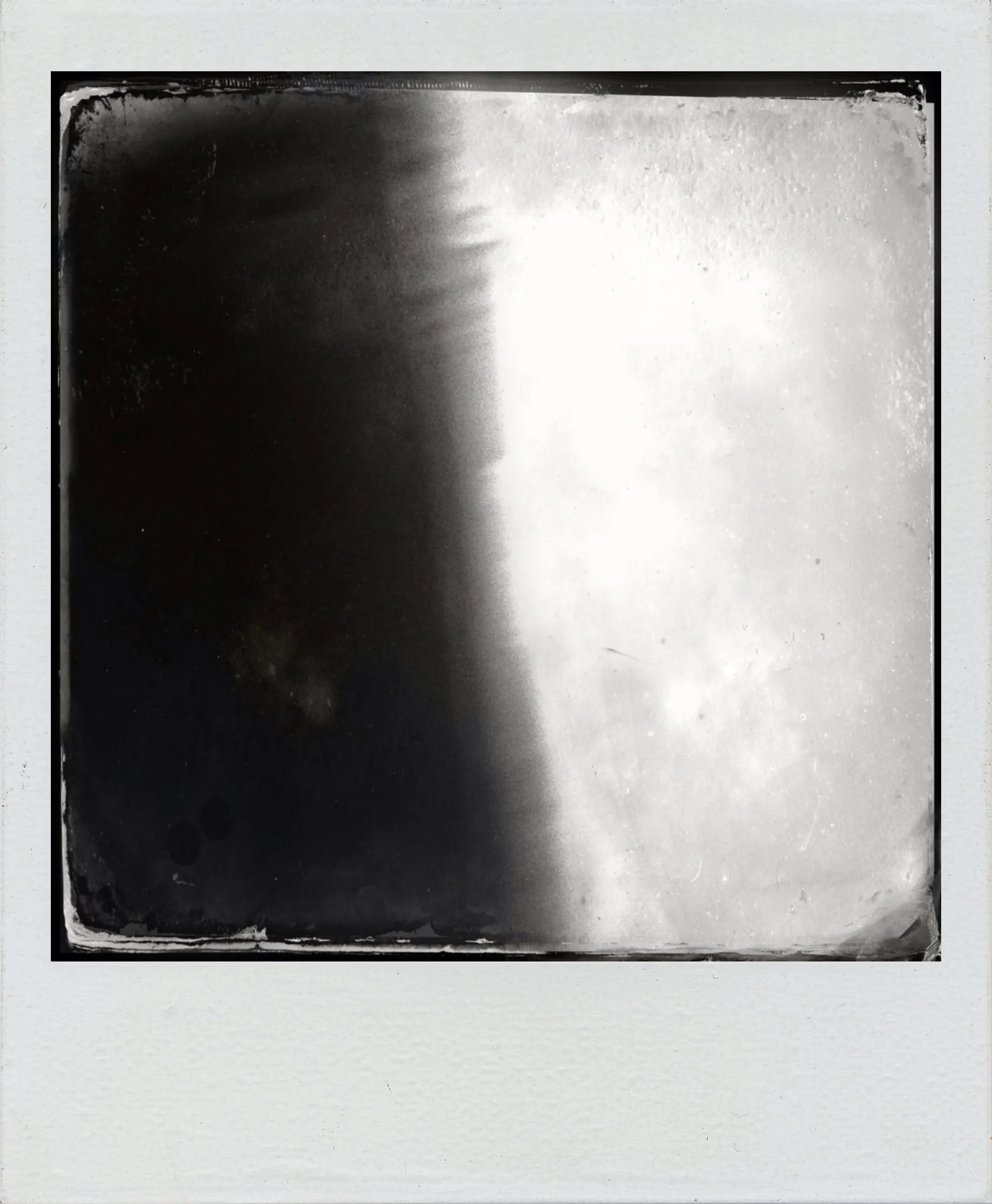 Black and white photo with a vertical gradient from dark left to light right, bordered by a white Polaroid-style frame.