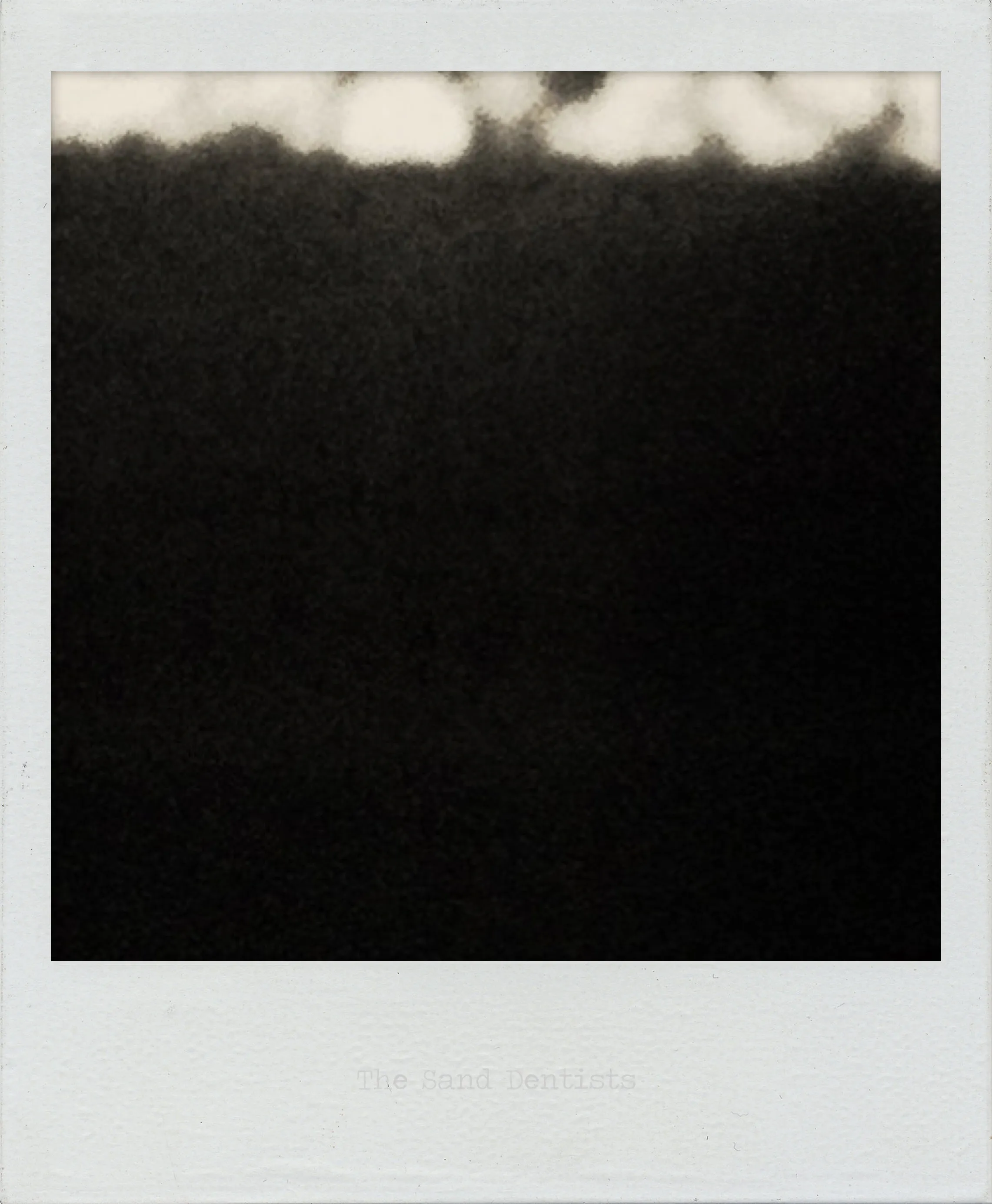 Grainy black-and-white image with a dark field occupying most of the frame and a jagged bright band along the top edge.