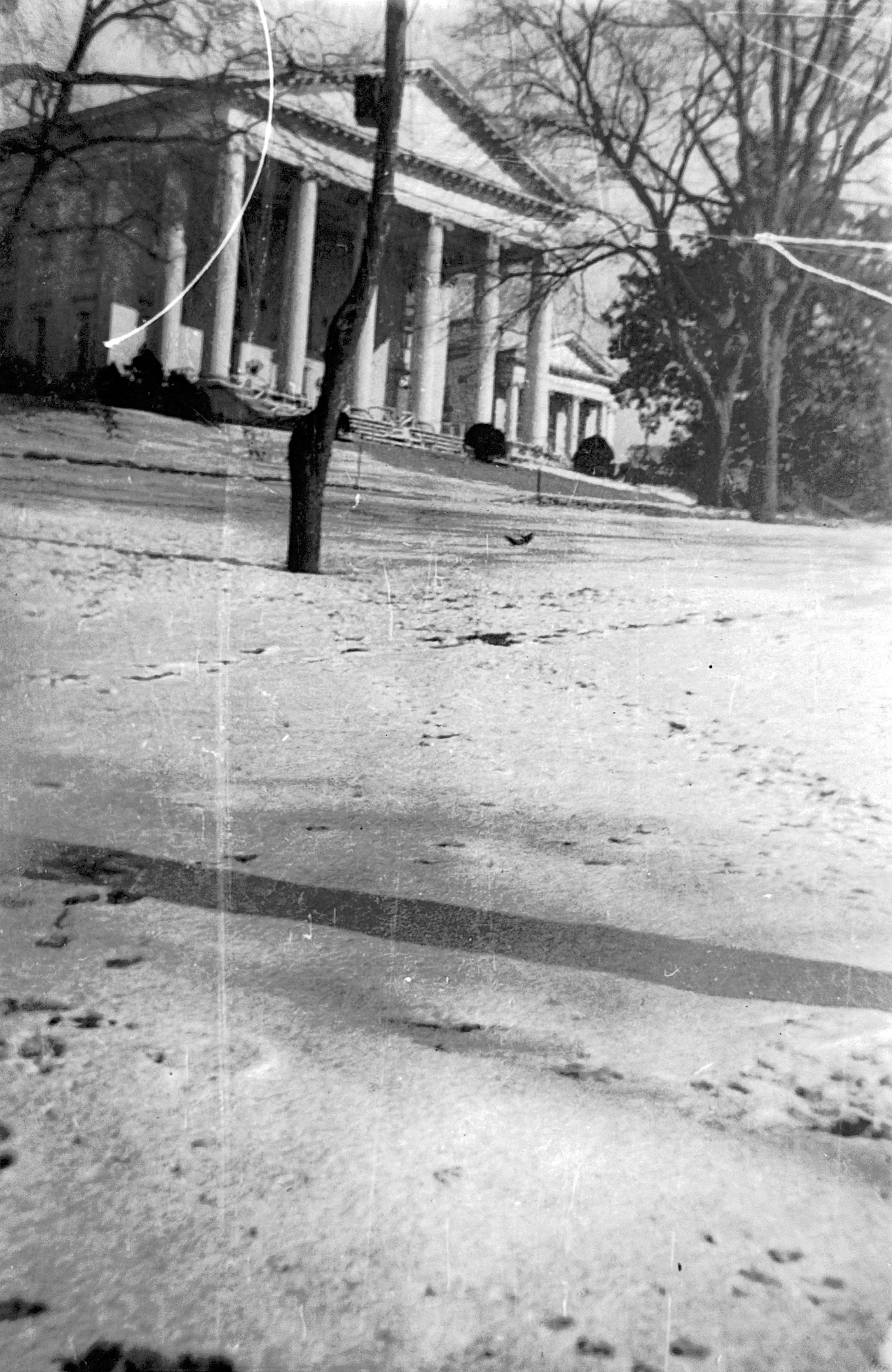 Damaged black and white photograph of neoclassical building with columns in winter snow