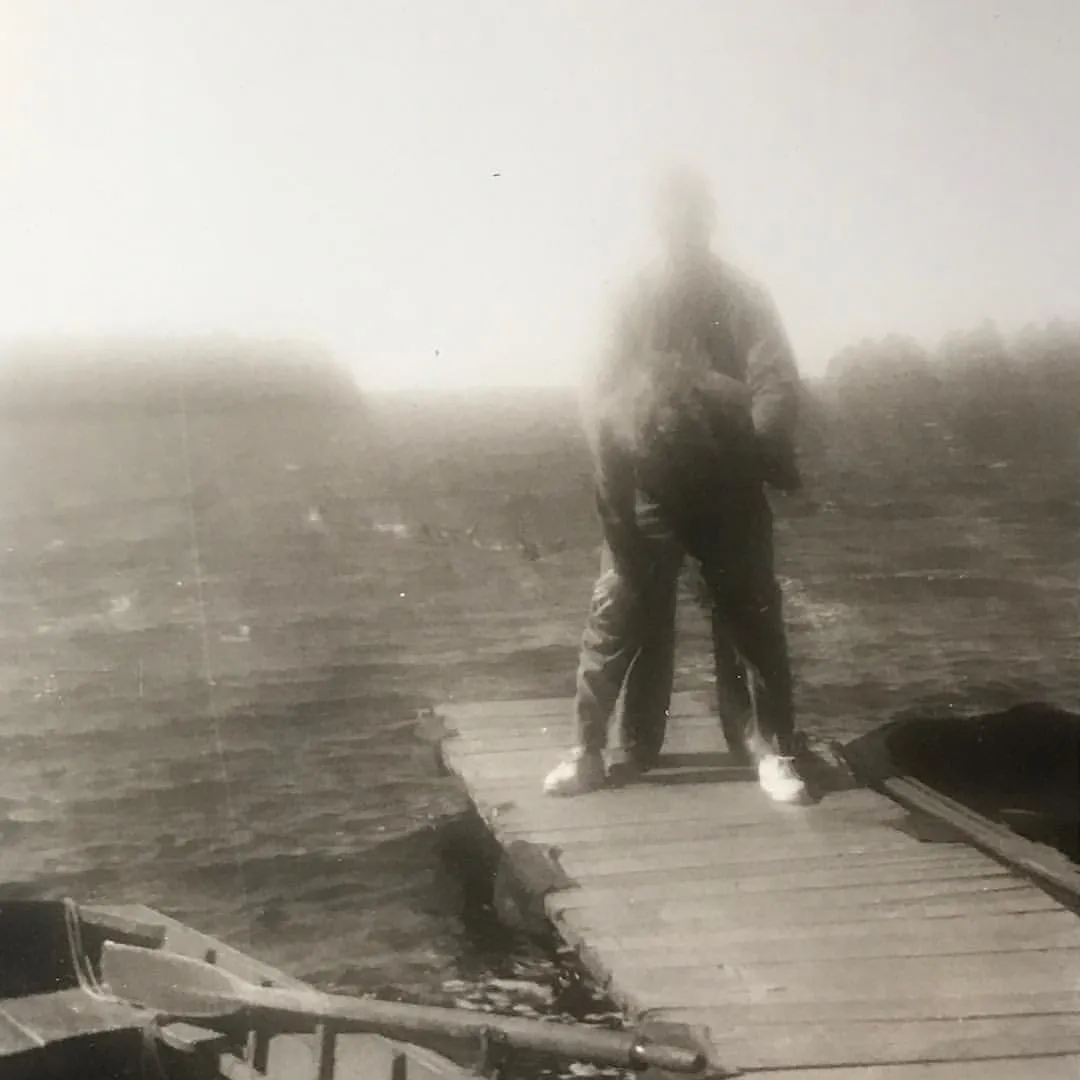 Vintage photograph of silhouetted figure standing on wooden dock in fog