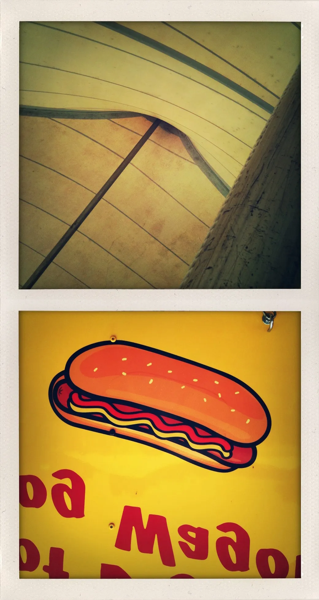 Yellow tent structure with curved support beams above; upside-down hot dog sign with red text on yellow background below.
